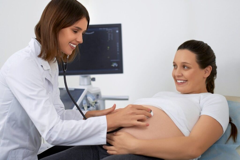 Pregnant woman receiving a prenatal checkup from an obstetrician during a routine maternity consultation in a modern hospital.Affordable Maternity Care in Thrissur